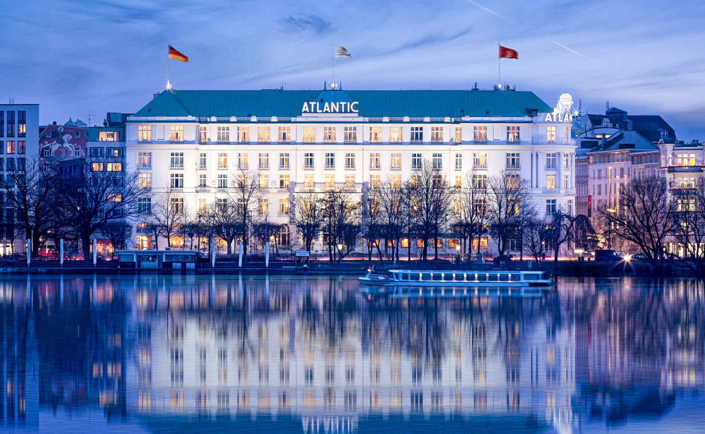 Referenzbild des Hotel Atlantic in Hamburg, Außenansicht des Hotels mit Spiegelungen im See